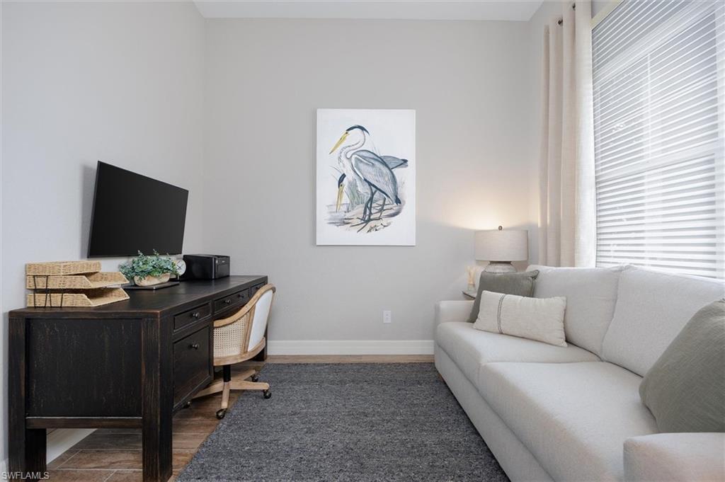 Flexible space featuring wood-finish flooring, light gray wall paint, and a window with blinds and drapes