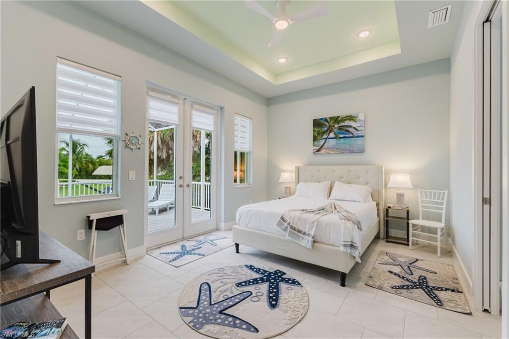 Recessed lighting, a tray ceiling, and a ceiling fan illuminate this space featuring light tile flooring