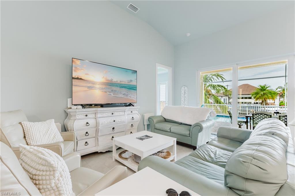 Vaulted ceiling living area featuring light-toned walls, wood-finish flooring, and expansive sliding glass doors opening to the outdoor space