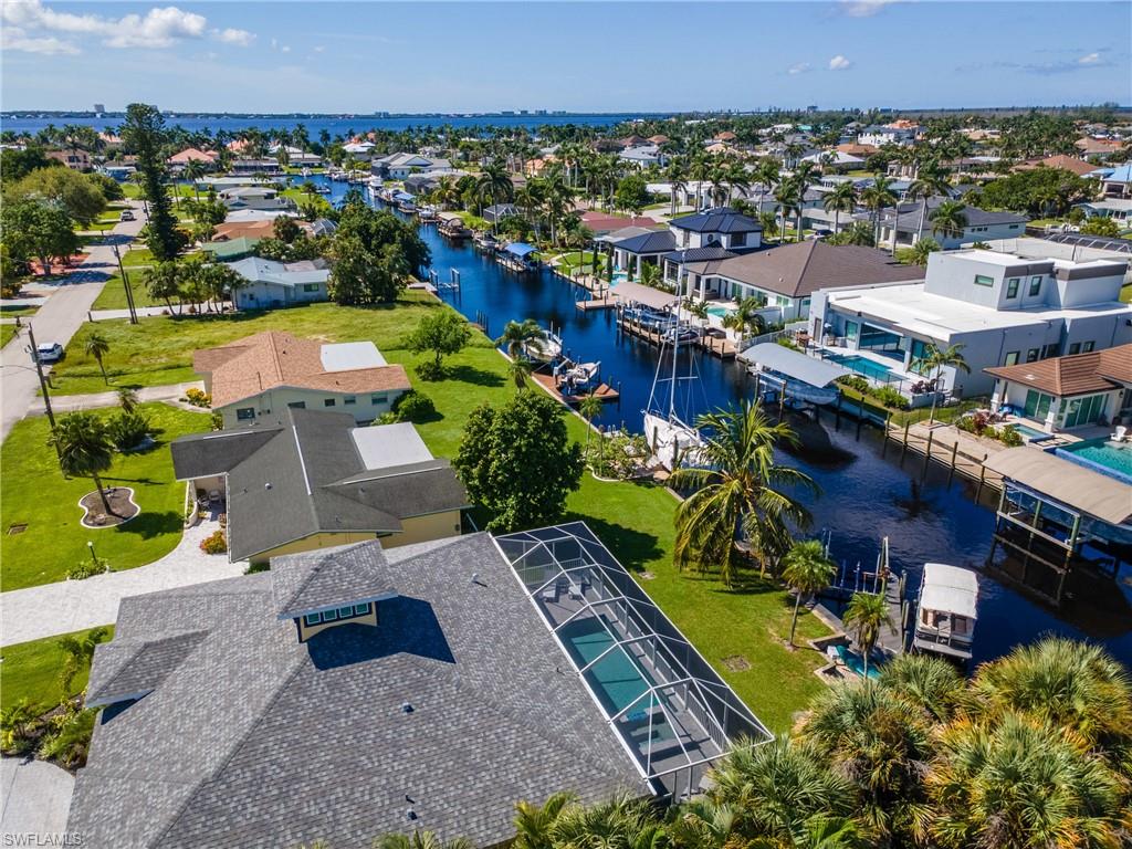 Canal-front property featuring a screened pool enclosure and mature landscaping