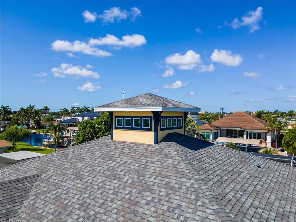 Asphalt shingle roof with a prominent cupola featuring multiple windows and a hip roof