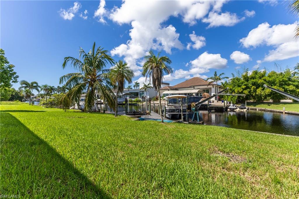 Expansive green lawn bordering a canal with multiple boat lifts and docks
