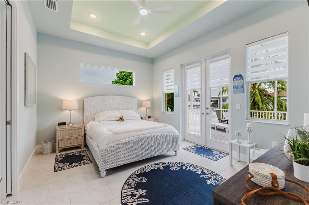 Interior room with light-toned tile flooring and a tray ceiling featuring recessed lighting and a ceiling fan
