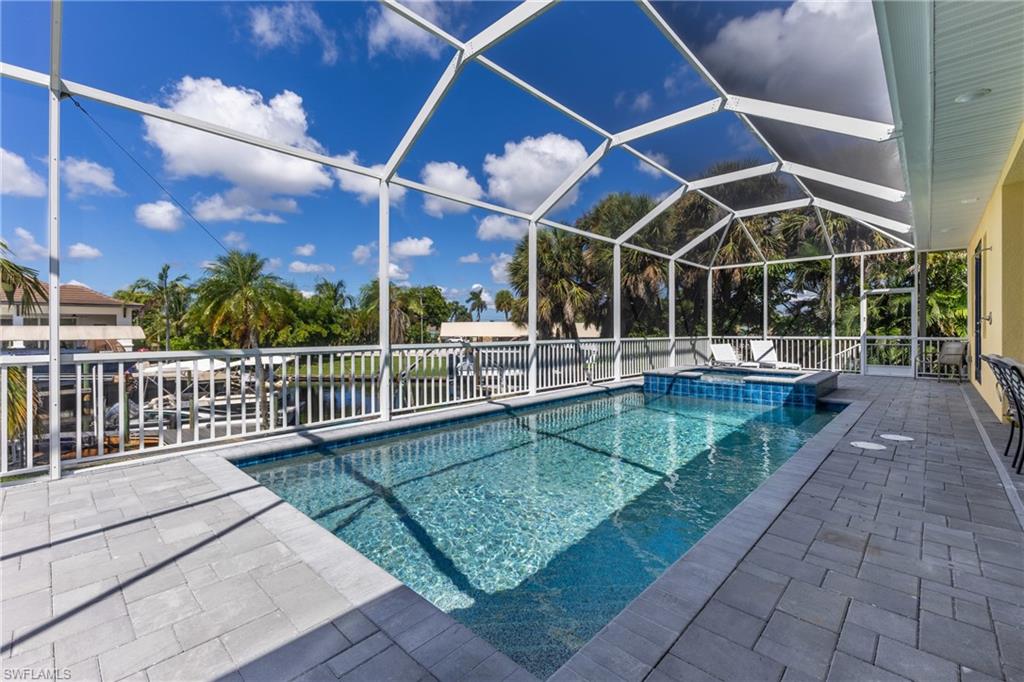 Screened pool enclosure featuring a rectangular pool, integrated spa, and paver decking