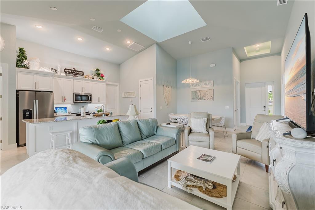 Open-concept living space featuring vaulted ceilings, two skylights, recessed lighting, and tile flooring