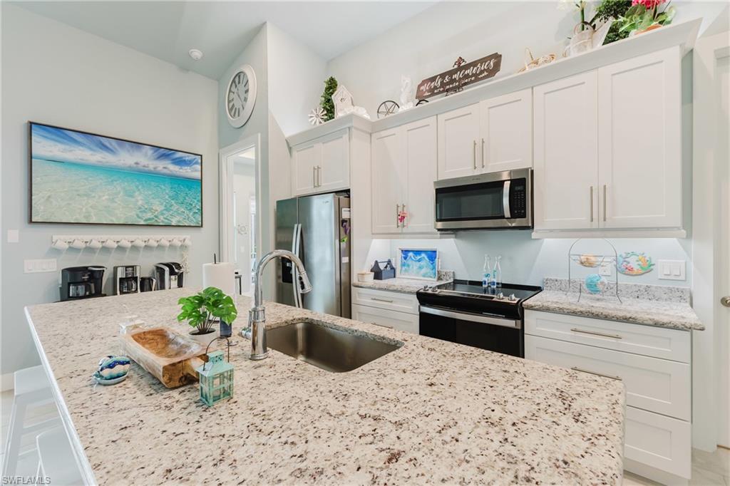 Kitchen featuring an expansive granite-finish island with an undermount sink and a gooseneck faucet