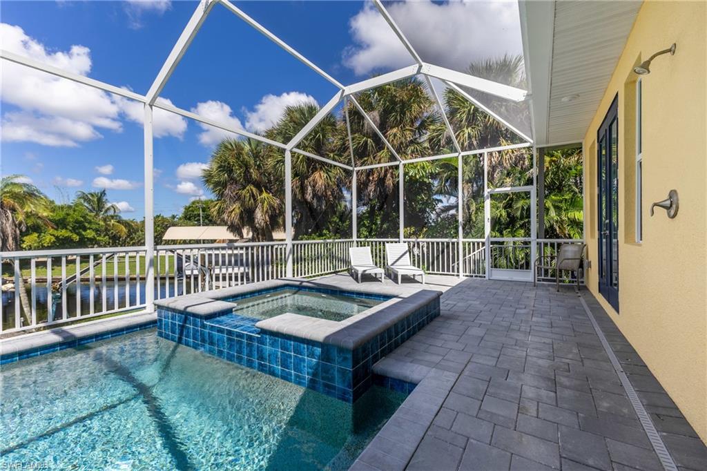 Screened outdoor living area featuring a built-in spa, rectangular pool, and paver decking