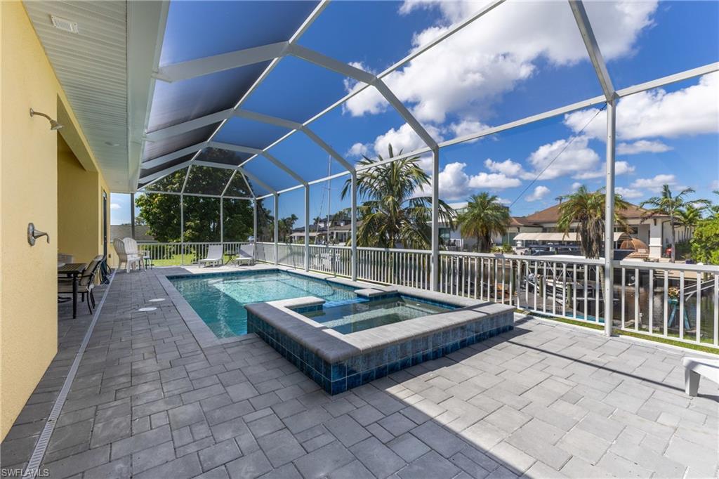 Screened lanai featuring a swimming pool, integrated spa, and extensive paver decking