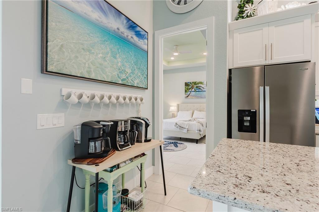 Kitchenette featuring white cabinetry, stainless steel refrigerator, and speckled countertop