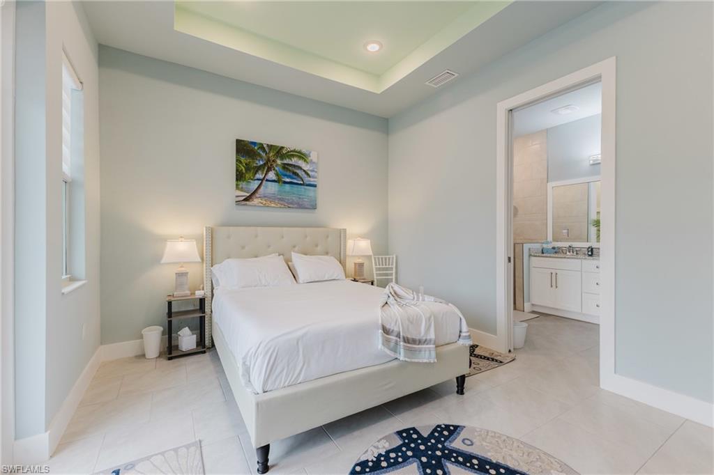 Spacious room featuring tray ceilings with recessed lighting, large format tile flooring, and a window for natural light
