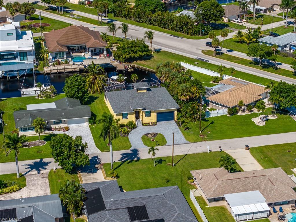 Canal-front property with a dock featuring a boat lift, an screened lanai, a concrete driveway, and a two-car garage