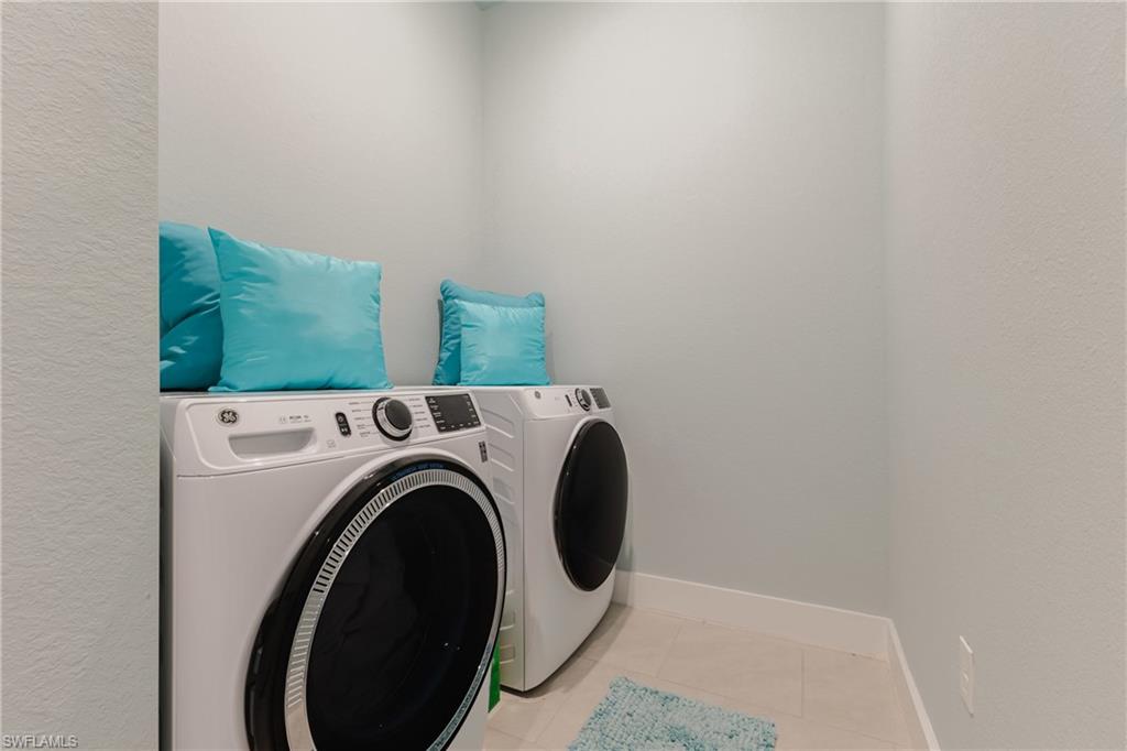 Dedicated laundry alcove featuring neutral wall paint, white baseboards, and tile flooring