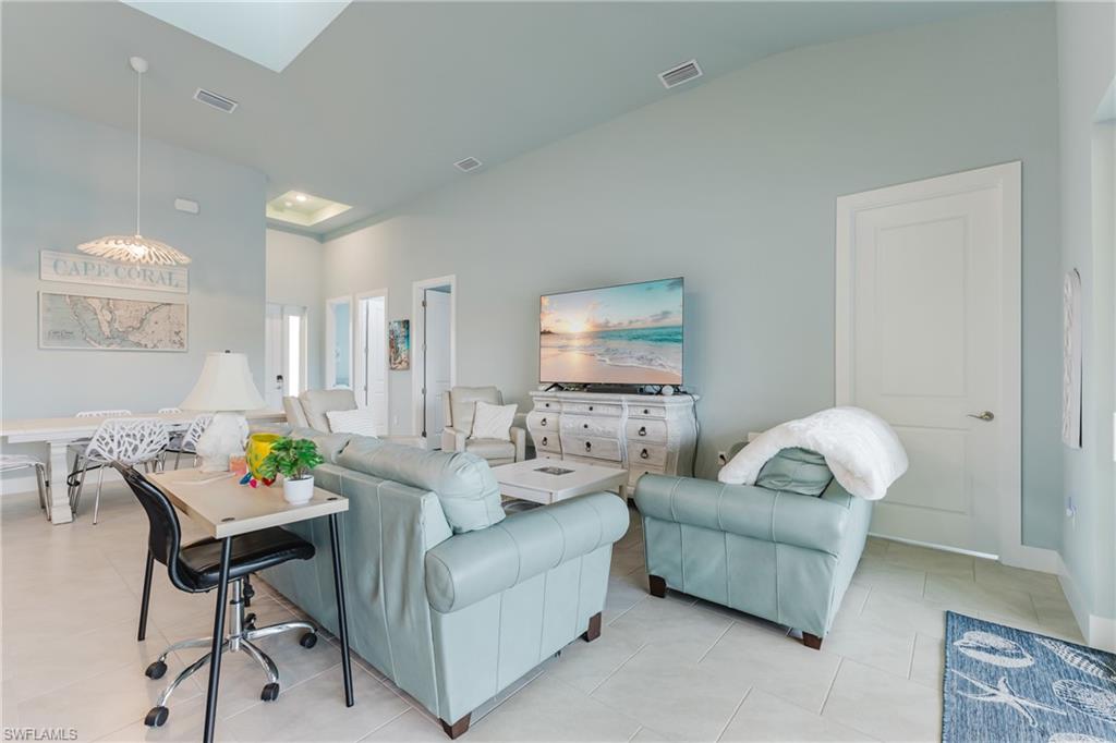 Open-concept living area featuring vaulted ceilings, recessed lighting, and light-toned tile flooring