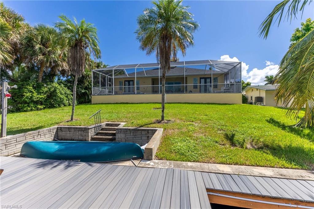 Waterfront property featuring a composite wood dock, screened-in patio, and lush green lawn