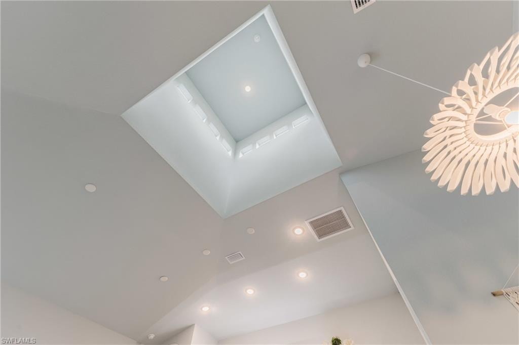 Vaulted ceiling featuring a large recessed skylight, multiple recessed light fixtures, and a decorative pendant light