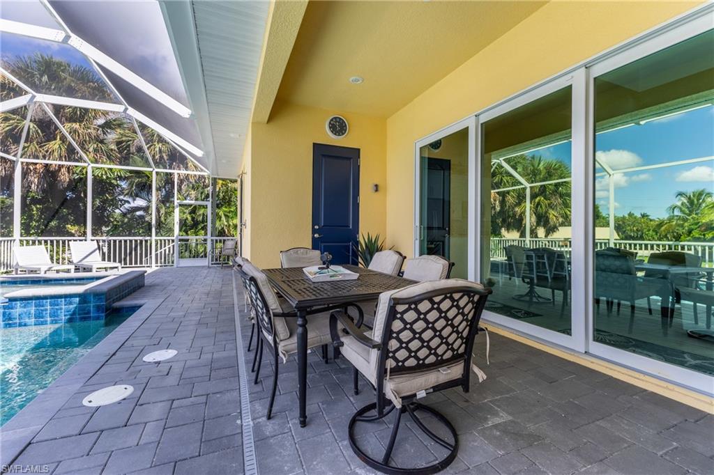 Screened lanai featuring a swimming pool, grey paver decking, yellow exterior wall, and multiple sliding glass doors