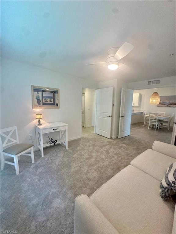 Living room with carpet flooring, a ceiling fan, and baseboards