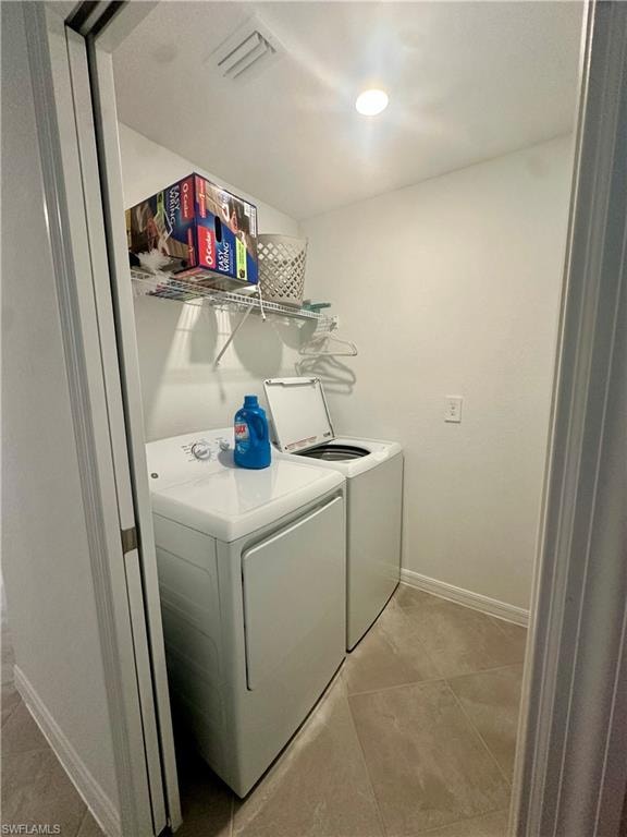 Washroom featuring washer and clothes dryer, baseboards, and light tile patterned floors