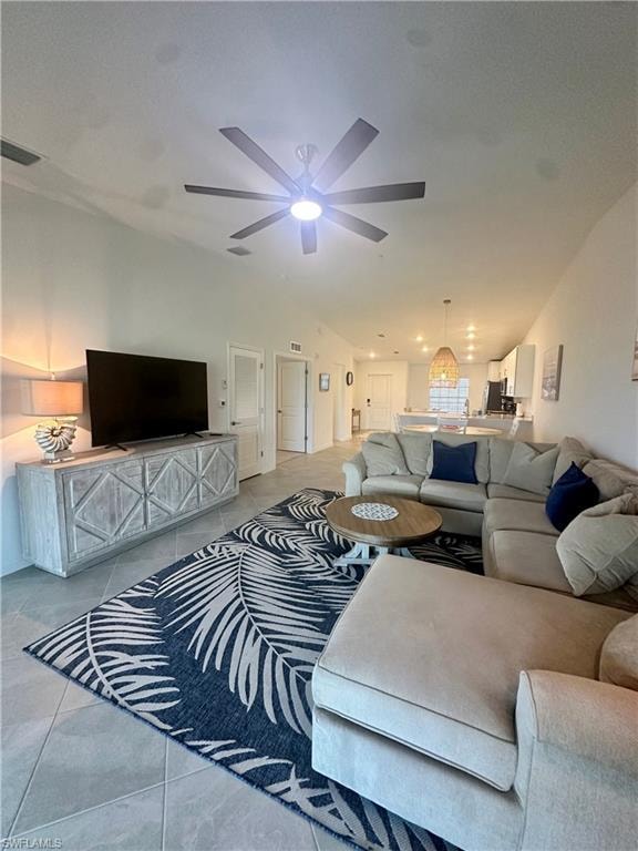 Living room featuring tile patterned flooring, ceiling fan, and vaulted ceiling