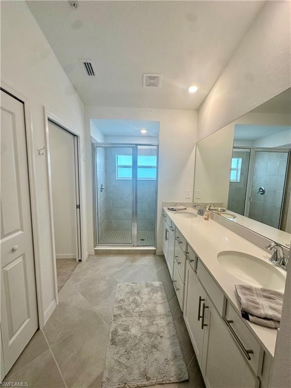 Full bathroom with a shower stall, double vanity, baseboards, and recessed lighting