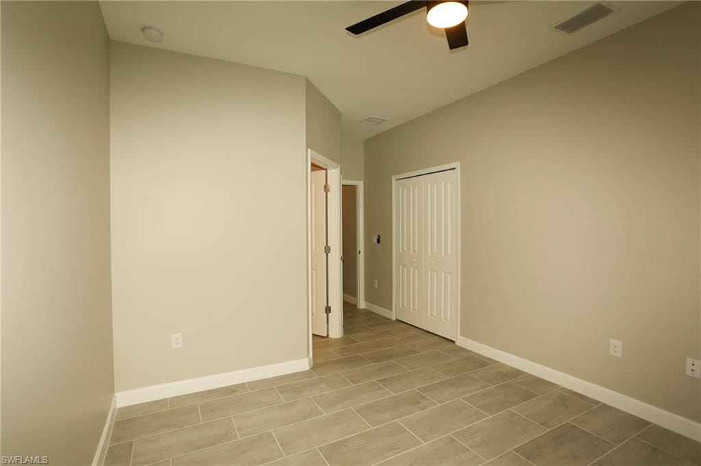 Interior room featuring tile flooring, neutral wall paint, white baseboards, and a ceiling fan with integrated lighting