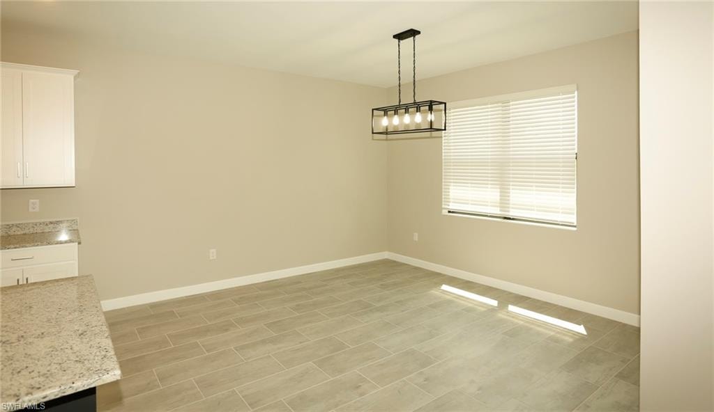 Dining area featuring a modern black linear chandelier, large window with blinds, and tile flooring