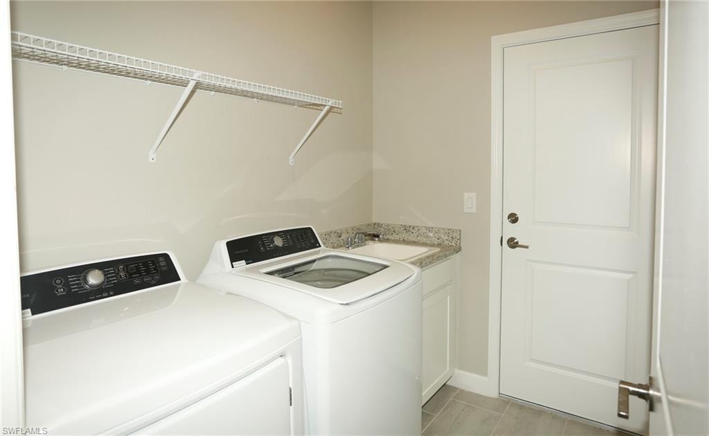 Dedicated utility space featuring a built-in sink, white cabinetry, a stone-finish countertop, and tile flooring