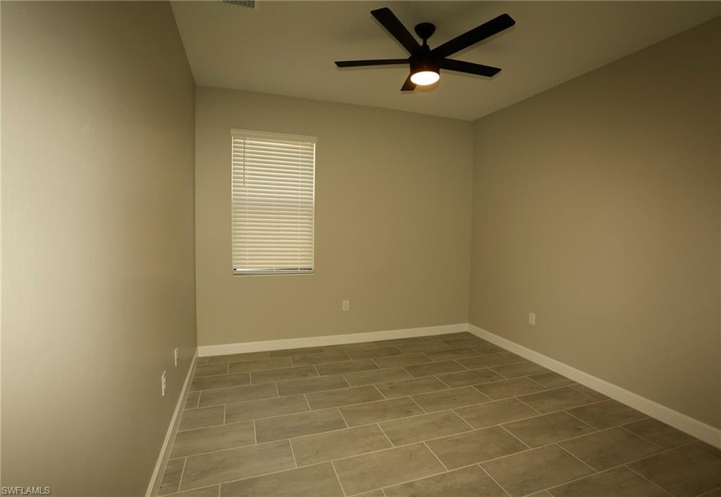 Spacious room featuring neutral tone walls, wood-finish tile flooring, a window with horizontal blinds, and a contemporary ceiling fan with integrated lighting