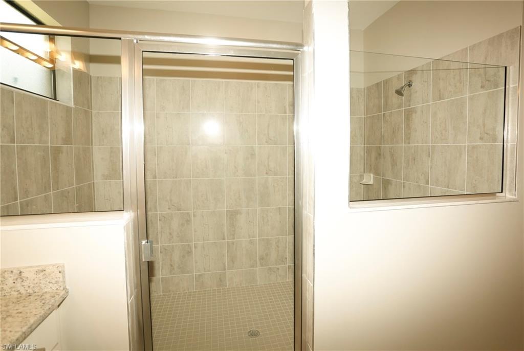 Glass-enclosed shower featuring tiled walls and a tiled floor