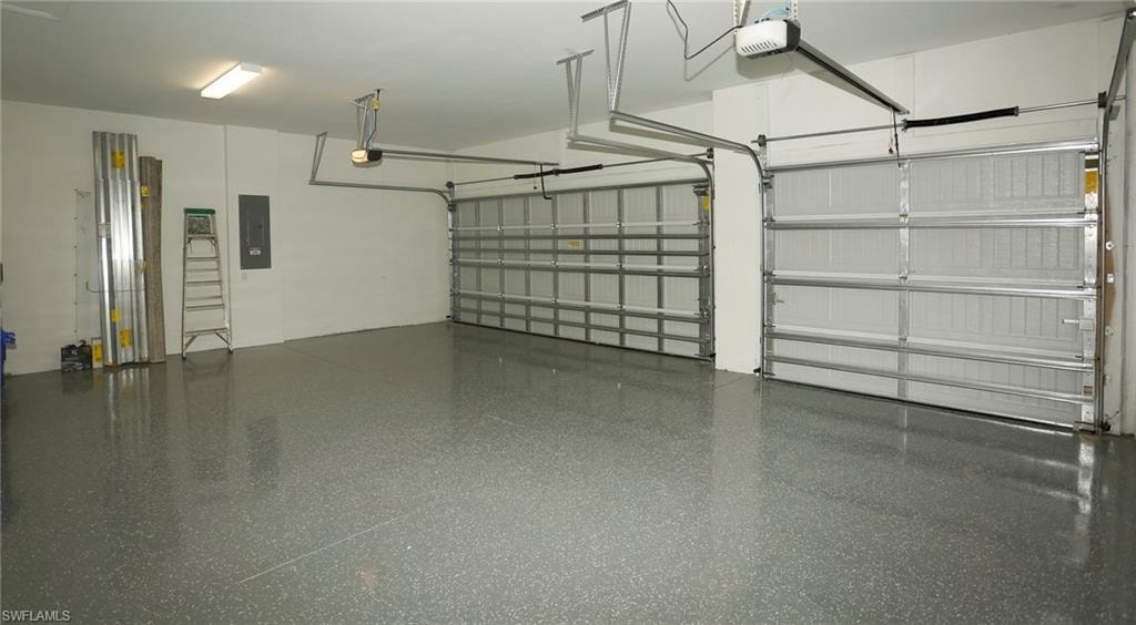 Spacious garage featuring two overhead doors, a speckled epoxy floor finish, and white painted walls