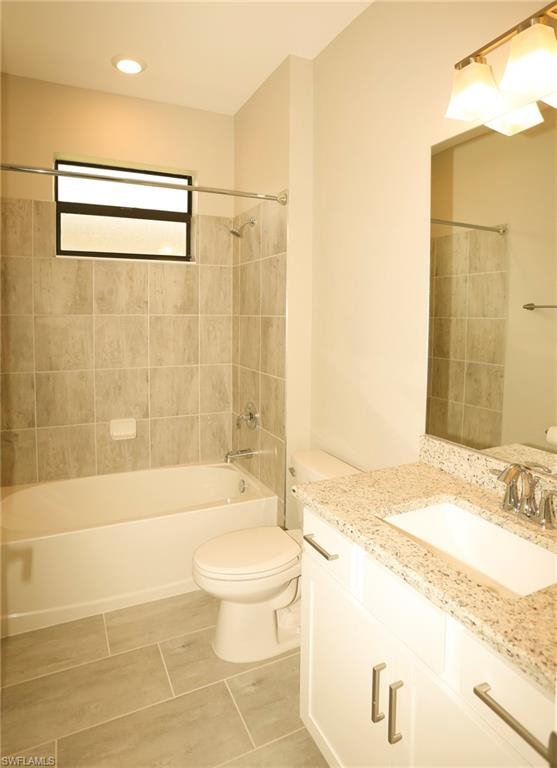 Contemporary bathroom featuring a tub/shower combination with light-toned tiled surround, a white vanity with a light granite countertop, and a rectangular undermount sink