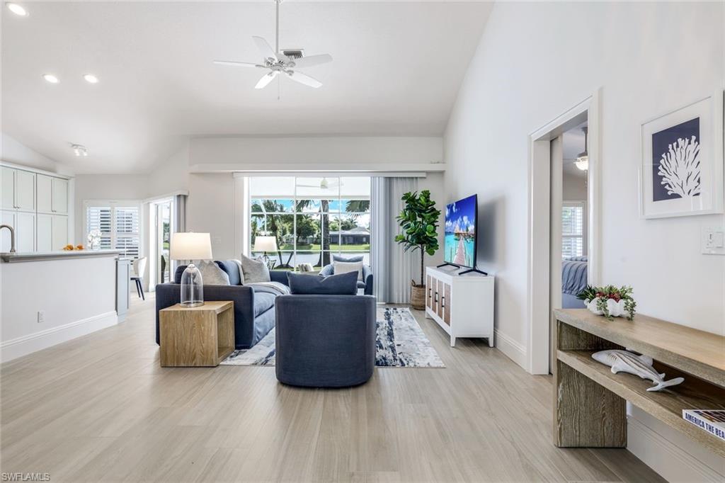 Living room featuring high vaulted ceiling, ceiling fan, and light hardwood / wood-style floors