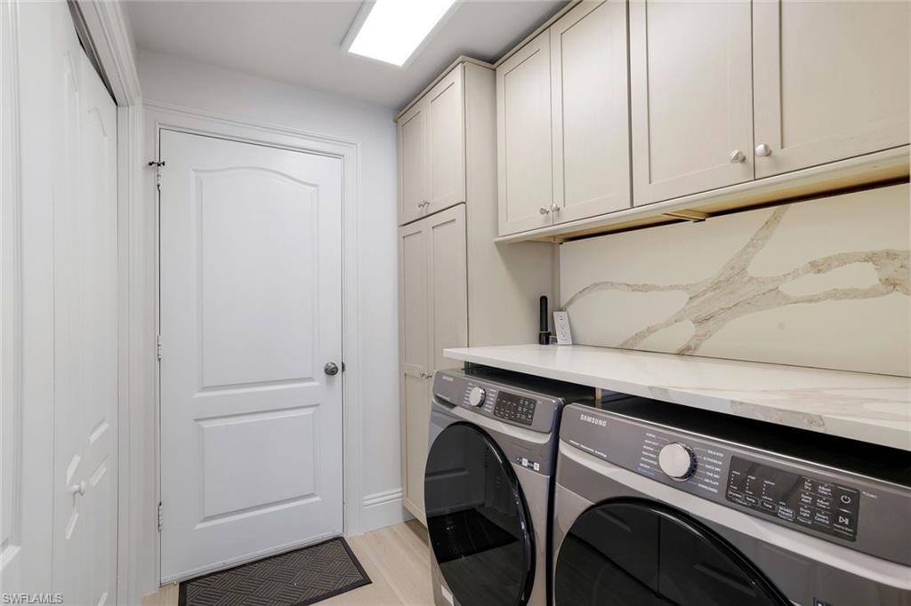 Laundry area with light hardwood / wood-style floors, cabinets, and washer and clothes dryer
