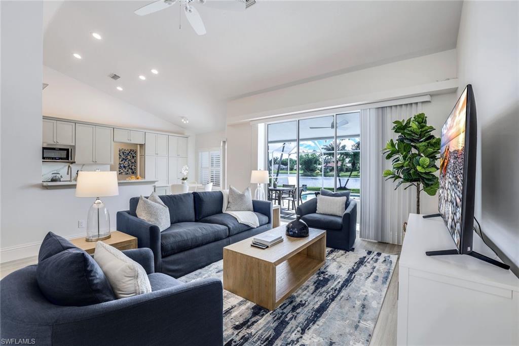 Living room with high vaulted ceiling, ceiling fan, and light hardwood / wood-style flooring