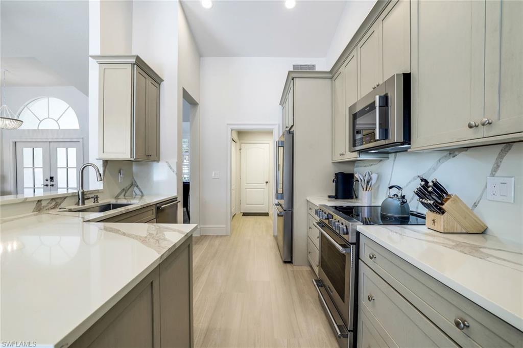 Kitchen featuring light stone counters, light hardwood / wood-style flooring, stainless steel appliances, gray cabinets, and sink