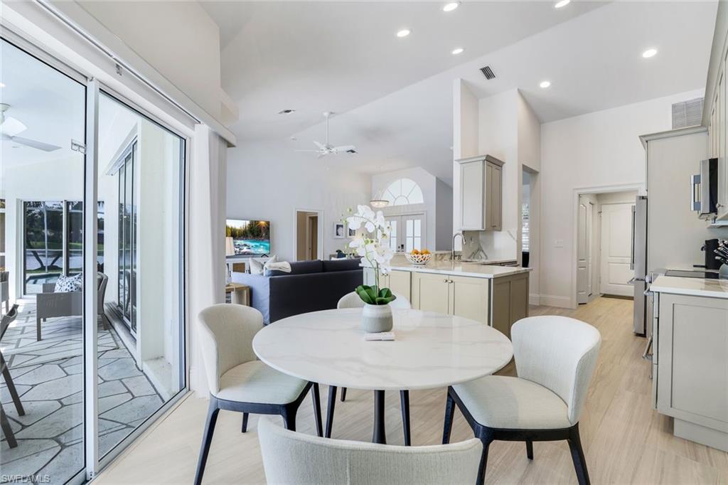 Dining room with high vaulted ceiling, ceiling fan, light hardwood / wood-style flooring, and sink