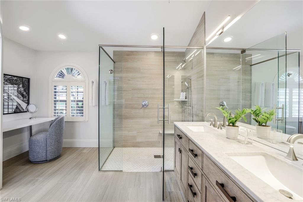 Bathroom featuring tile floors, walk in shower, vanity with extensive cabinet space, and double sink