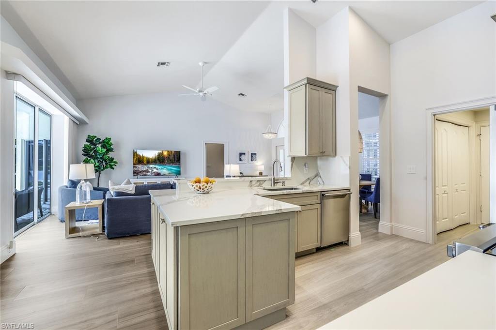Kitchen with dishwasher, ceiling fan, light stone countertops, light wood-type flooring, and sink