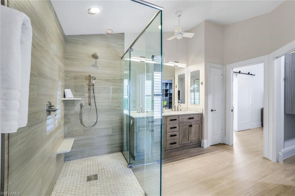 Bathroom featuring hardwood / wood-style flooring, vanity, ceiling fan, and a shower with door