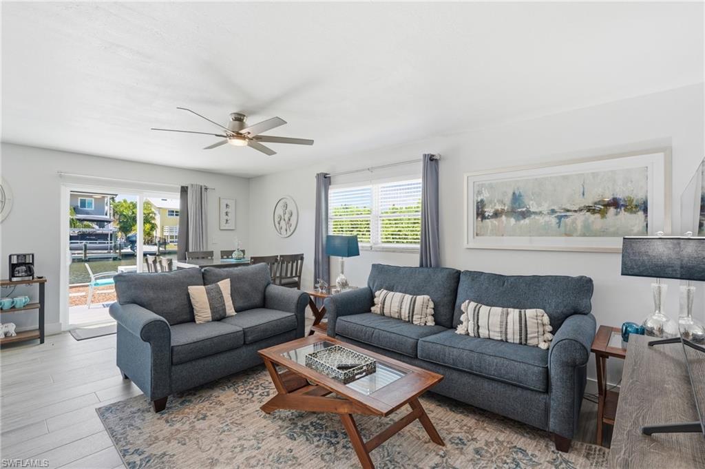 Open-concept living area featuring light wood-finish flooring and a ceiling fan - Virtually Edited Image