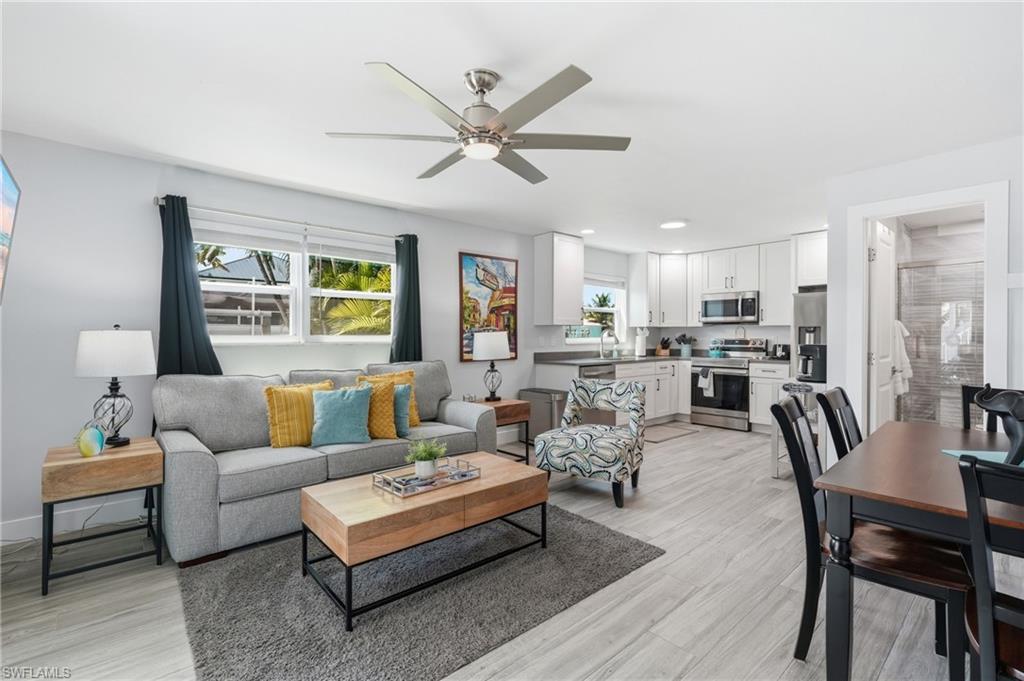 Open-concept living area featuring light wood-finish flooring, a contemporary ceiling fan, and recessed lighting - Virtually Edited Image