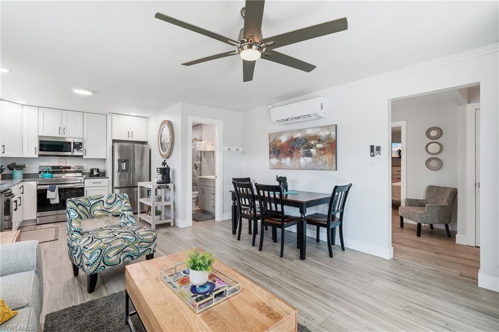 Open-concept living area featuring wood-finish flooring, a contemporary ceiling fan, and recessed lighting - Virtually Edited Image
