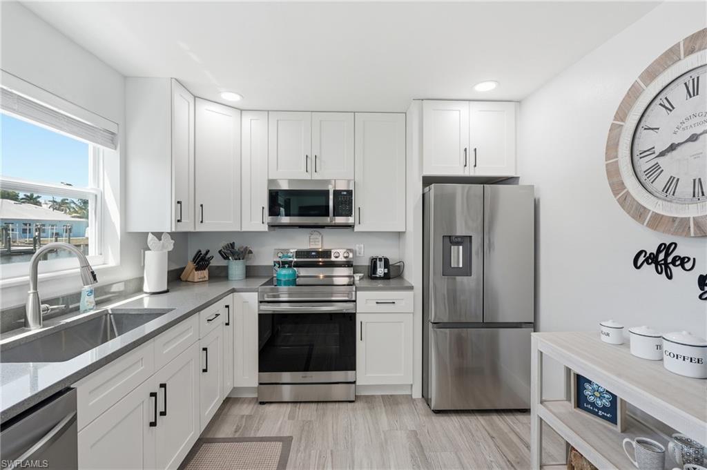 Modern kitchen featuring white shaker-style cabinetry, stainless steel appliances, and a double-basin undermount sink - Virtually Edited Image
