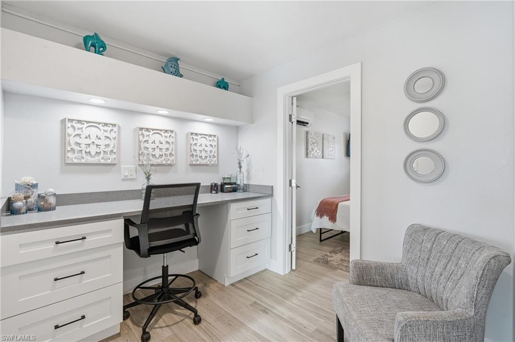 Dedicated workspace featuring white cabinetry, a light gray countertop, and built-in lighting - Virtually Edited Image
