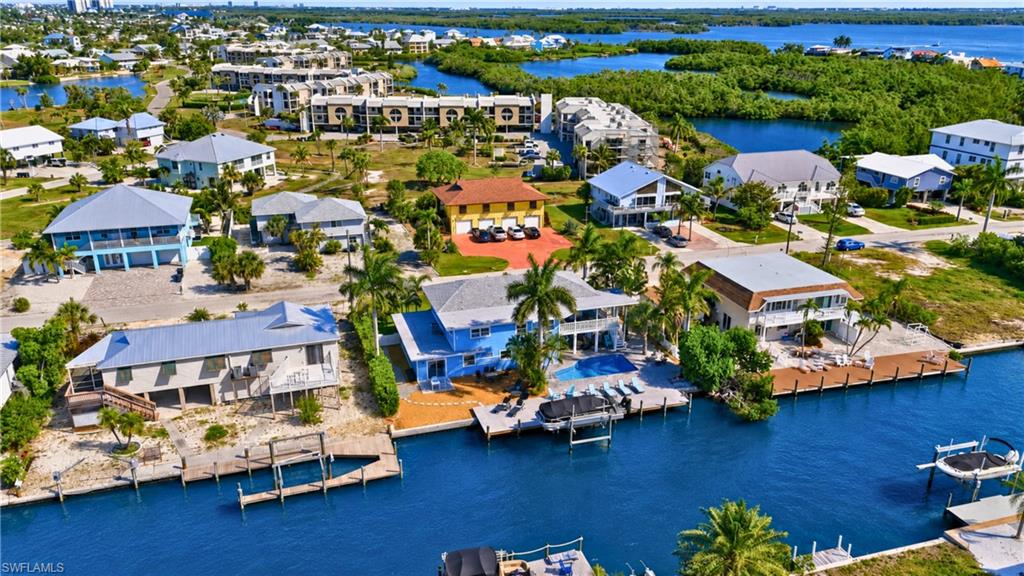 Waterfront property featuring a private boat dock, backyard swimming pool, and multiple palm trees - Virtually Edited Image
