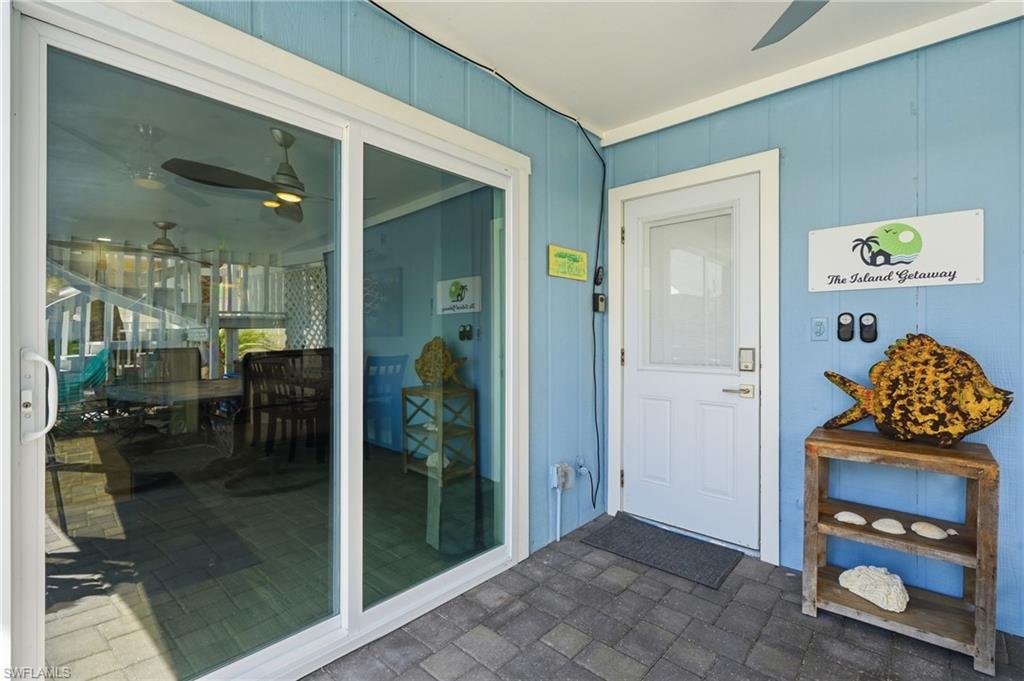 Light blue vertical plank siding exterior featuring a white entry door with a window insert and a white frame sliding glass door - Virtually Edited Image