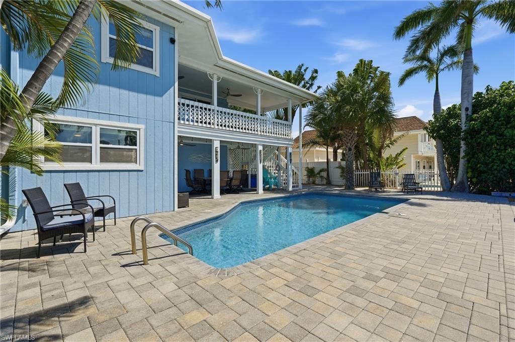 Rectangular swimming pool with integrated steps, surrounded by a paver patio and tropical landscaping - Virtually Edited Image