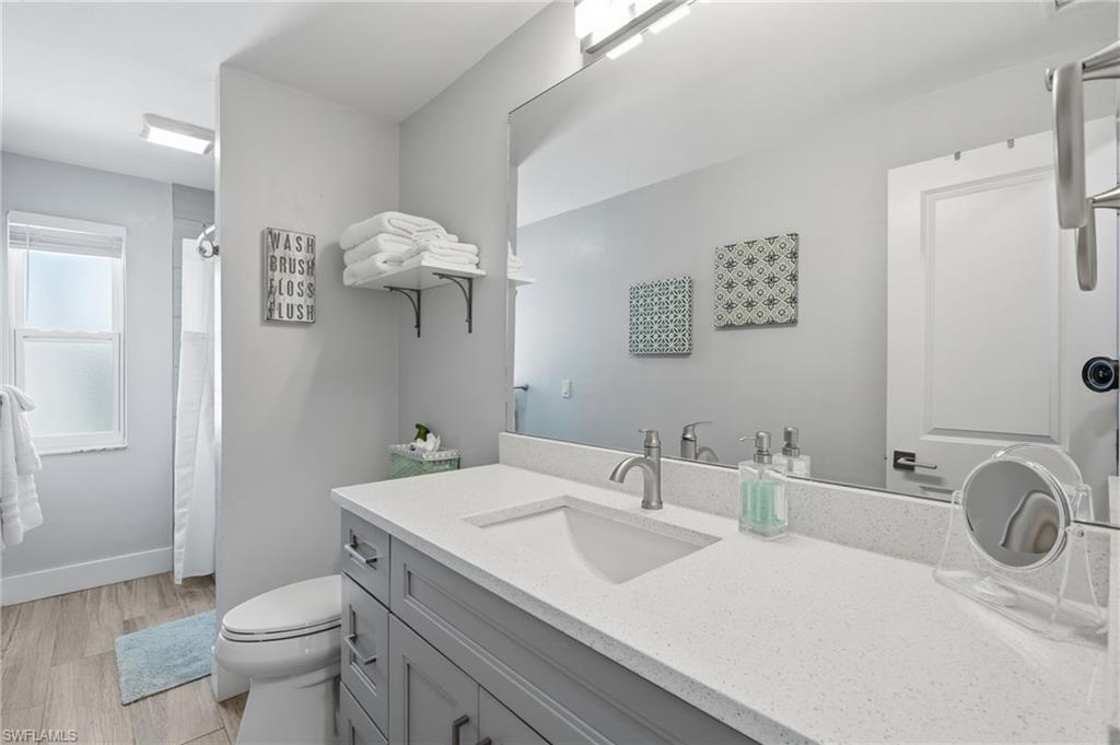 Modern bathroom featuring a gray vanity with a light-toned countertop, an integrated rectangular sink, and brushed nickel fixtures - Virtually Edited Image