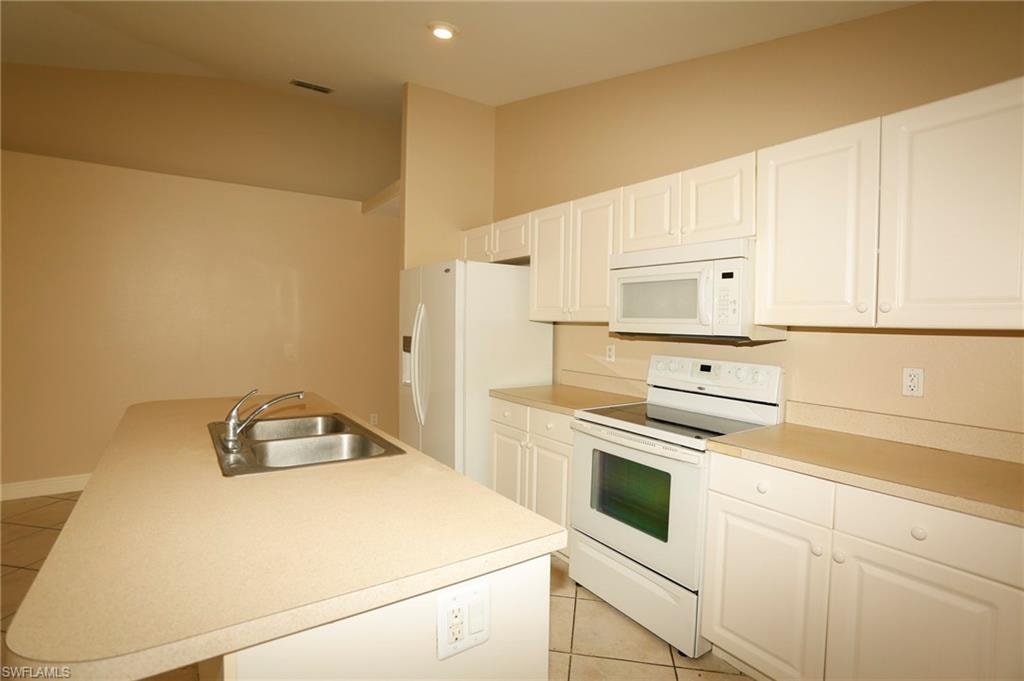 Kitchen featuring a central island with an integrated double basin sink and chrome faucet