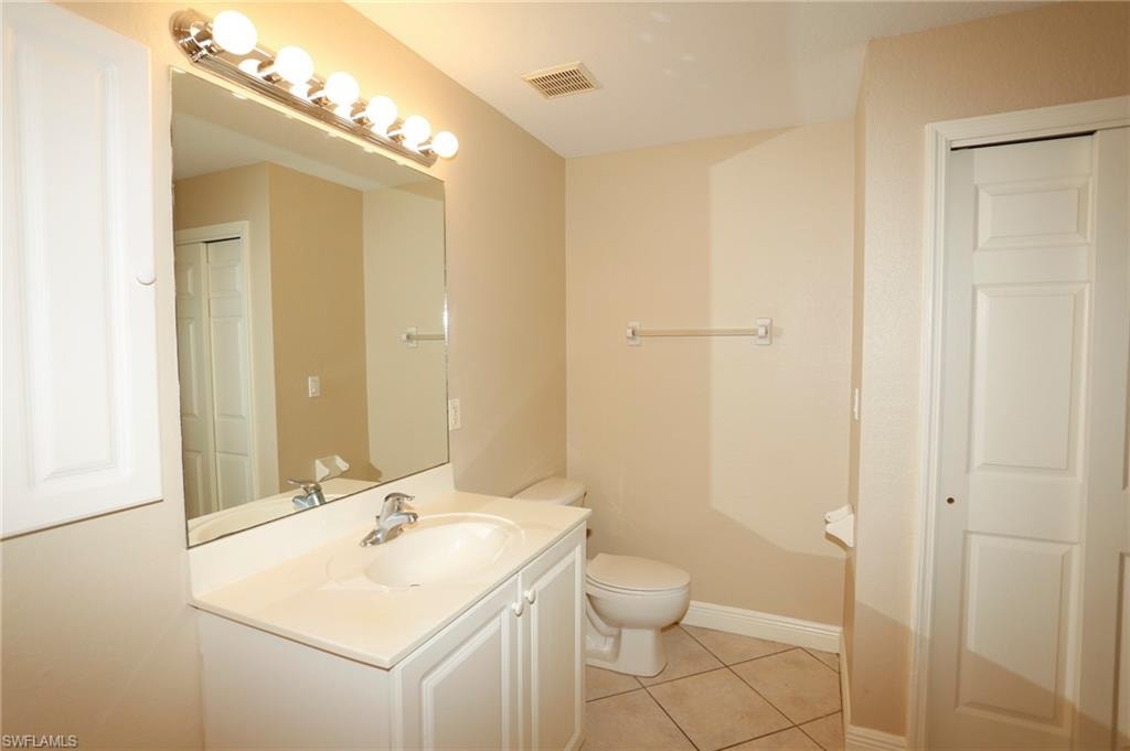 Bathroom featuring a single vanity with an integrated sink, polished chrome faucet, and overhead bar lighting